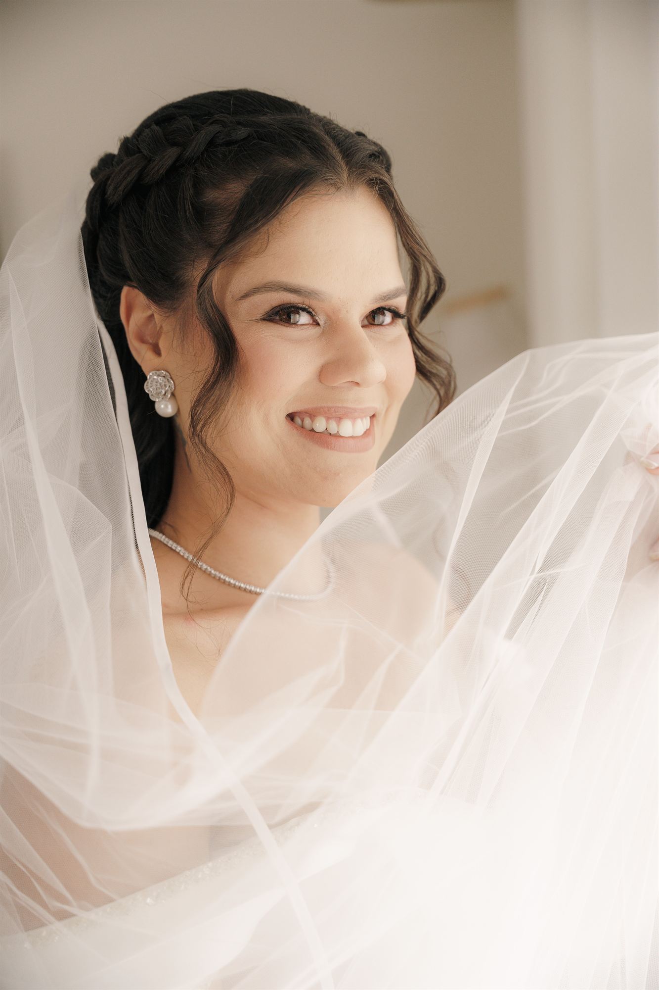 Noiva sorrindo envolta no véu de tule